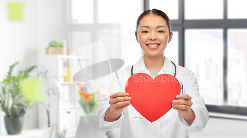 Image of smiling asian female doctor holding red heart