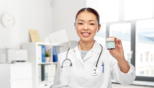 Image of smiling female doctor holding jar of medicine