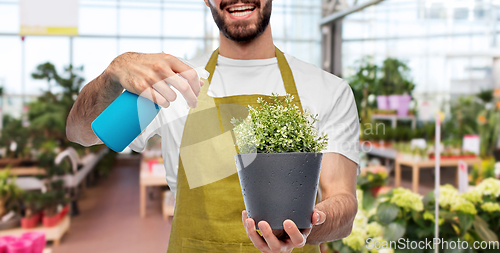 Image of happy gardener or farmer with sprayer and flower