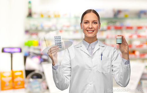 Image of smiling female doctor holding medicine at pharmacy