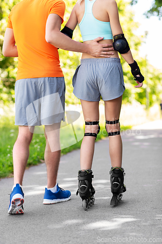 Image of happy couple with roller skates riding outdoors