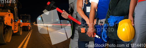 Image of Builder workers with equipment repairing a road