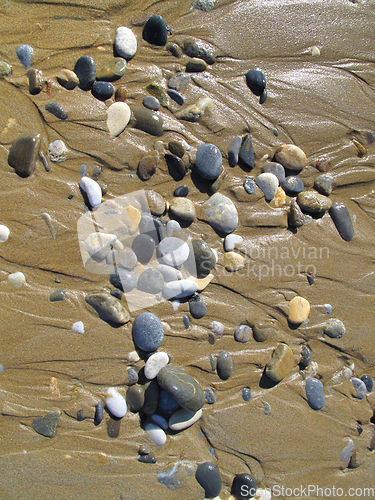 Image of Wet sea pebbles on the sand