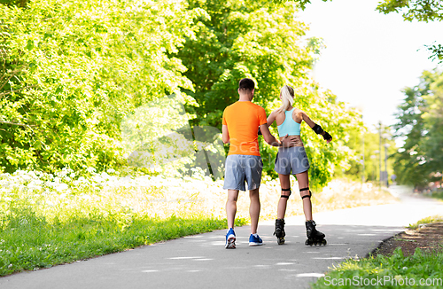 Image of happy couple with roller skates riding outdoors