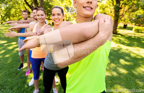 Image of happy people exercising with trainer at park