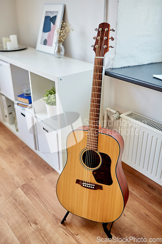 Image of close up of acoustic guitar on stand at home