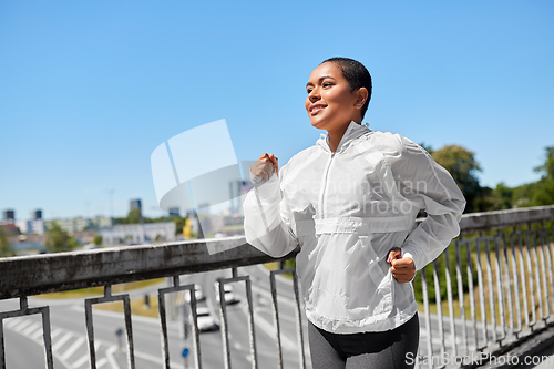 Image of african american woman running along bridge