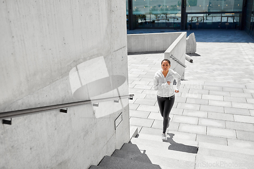 Image of african american woman running upstairs outdoors