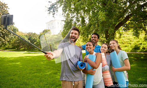 Image of people with yoga mats taking selfie at park