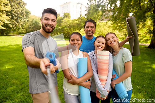 Image of people with yoga mats taking selfie at park