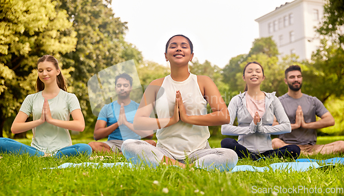 Image of group of people doing yoga at summer park