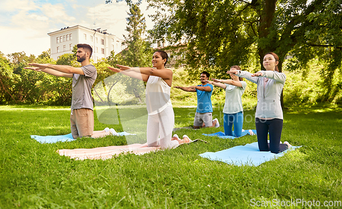 Image of group of people doing yoga at summer park