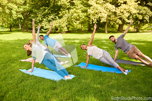 Image of group of people doing yoga at summer park