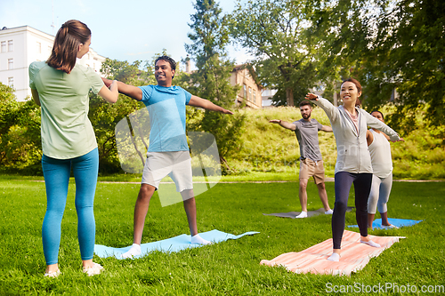 Image of group of people doing yoga with instructor at park