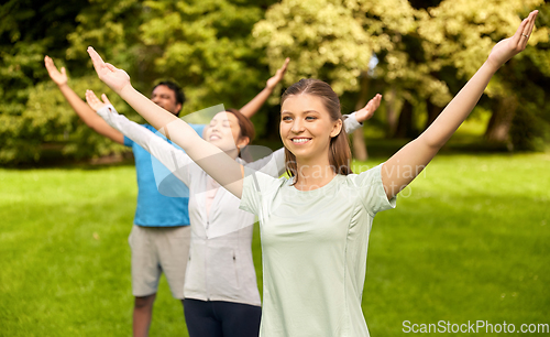 Image of group of people doing yoga at summer park