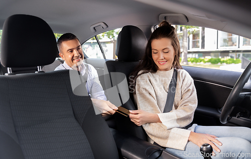 Image of female car driver takes credit card from passenger