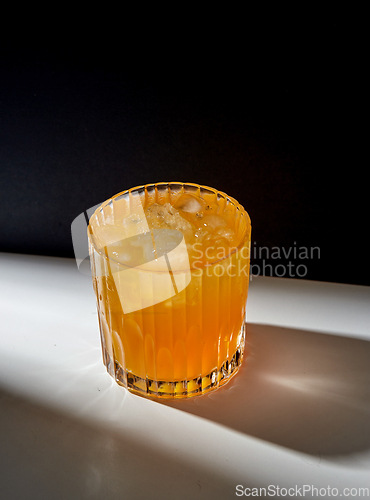 Image of glass of orange juice with ice on table