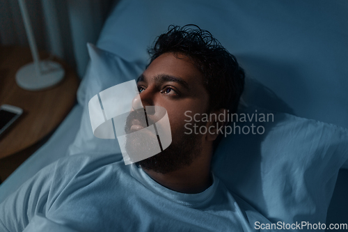 Image of speelpess indian man lying in bed at night