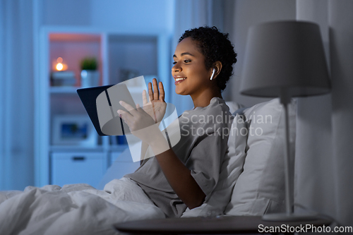 Image of woman with tablet pc in bed has video call