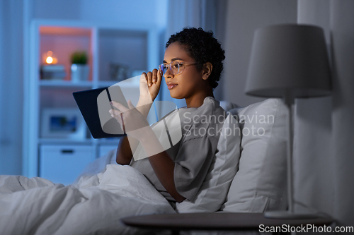 Image of woman with tablet pc in bed at home at night