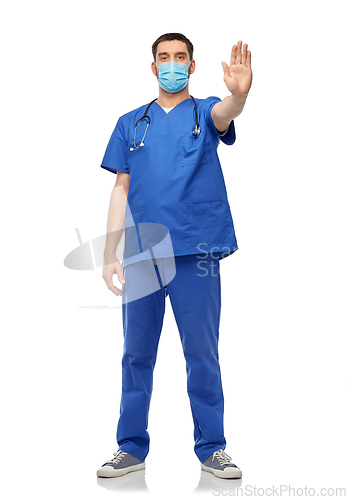 Image of male doctor in blue uniform and mask showing stop