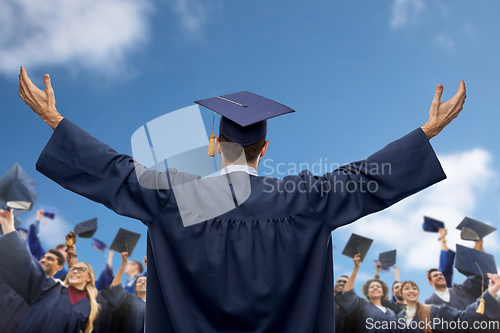 Image of happy students or bachelors waving mortar boards