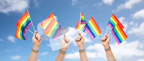 Image of hands with gay pride rainbow flags and wristband