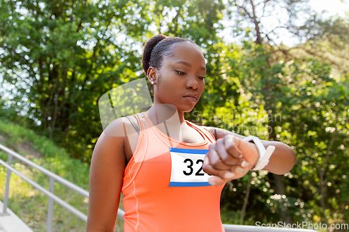 Image of african female marathon runner with smart watch