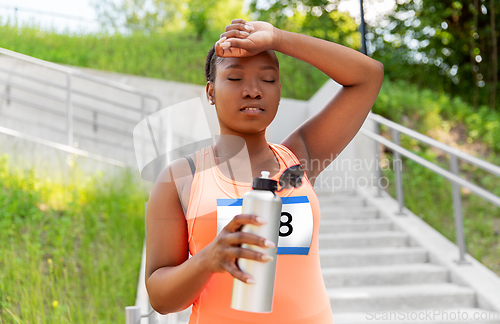 Image of tired female marathon runner with bottle of water