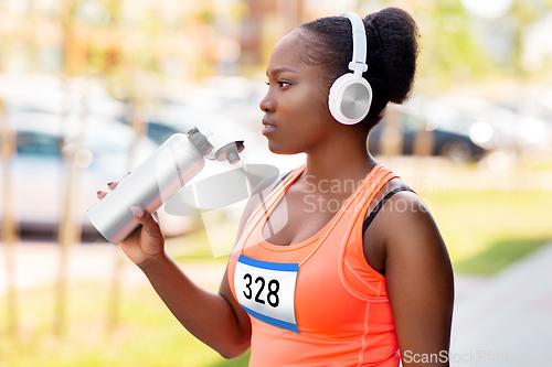 Image of african female marathon runner drinking water