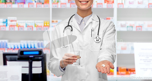 Image of female doctor with medicine and water at pharmacy