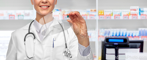 Image of smiling female doctor showing medicine at pharmacy