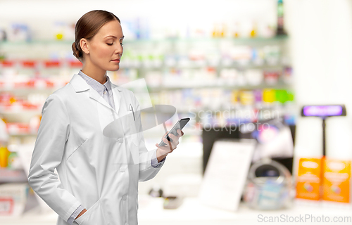 Image of female doctor with smartphone at pharmacy