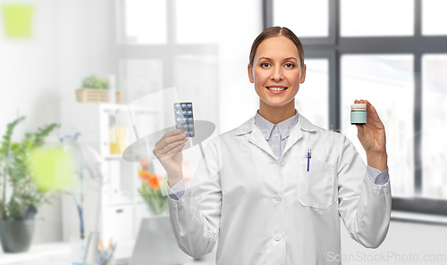 Image of smiling female doctor holding medicine at hospital