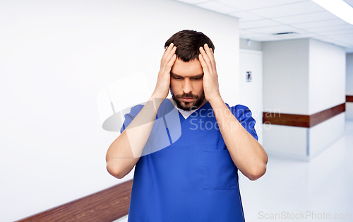 Image of stressed doctor or male nurse in blue uniform