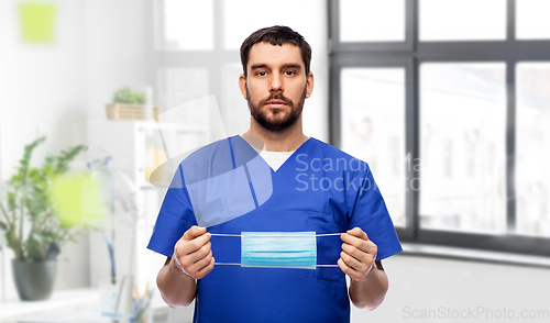 Image of male doctor in blue uniform with mask