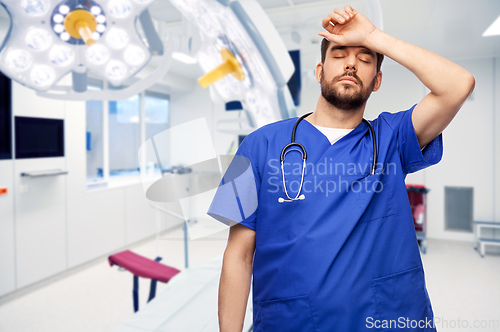 Image of tired doctor or male nurse at surgery in hospital