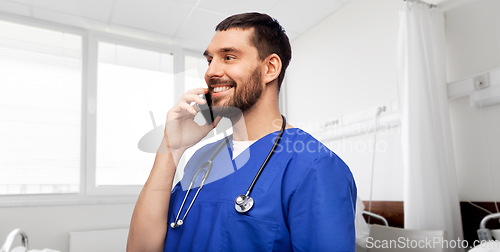 Image of smiling doctor or male nurse calling on smartphone