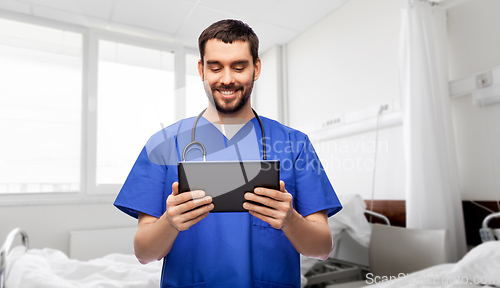 Image of smiling doctor or male nurse using tablet computer