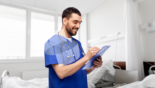 Image of male doctor writing medical report on clipboard