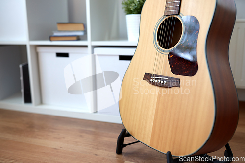 Image of close up of acoustic guitar on stand at home