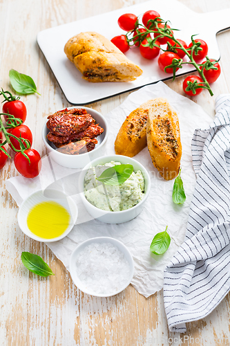 Image of Avocado spread and sun dried tomatoes with olive oil as antipasto and baguette