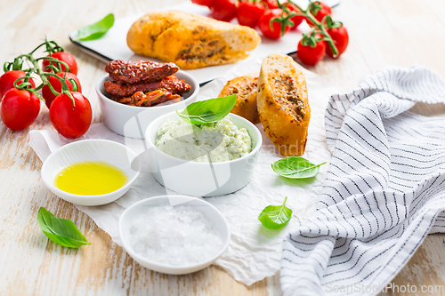 Image of Avocado spread and sun dried tomatoes with olive oil as antipasto and baguette