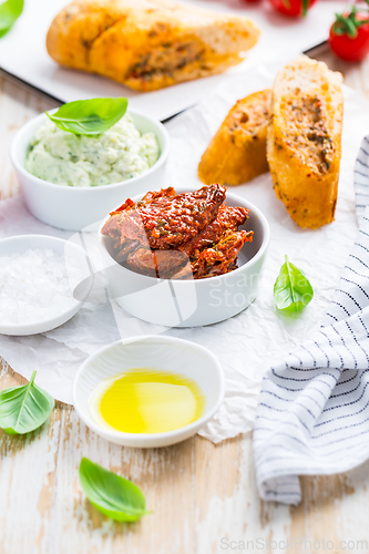 Image of Sun dried tomato with olive oil as antipasto with avocado spread and baguette