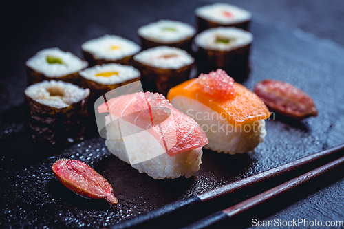 Image of Assortment of vegan sushi with vegetables, seitan, Konjac plant, tofu as fish substitutes, with finger lime as caviar on black