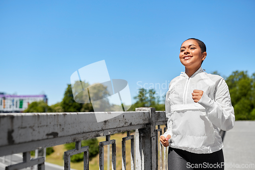 Image of african american woman running along bridge