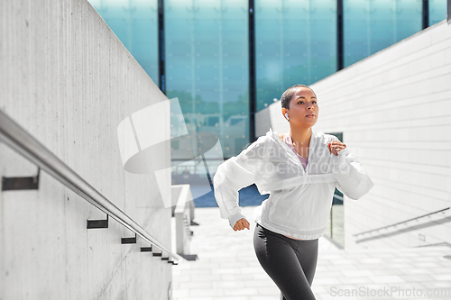 Image of african american woman running upstairs outdoors