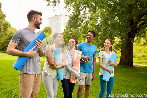 Image of group of happy people with yoga mats at park