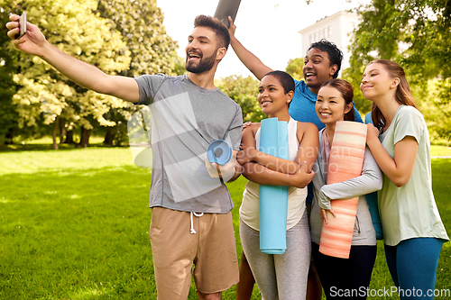 Image of people with yoga mats taking selfie at park