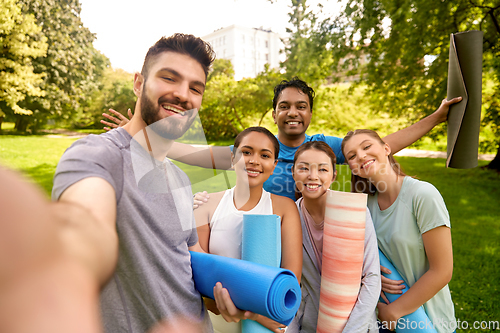 Image of people with yoga mats taking selfie at park